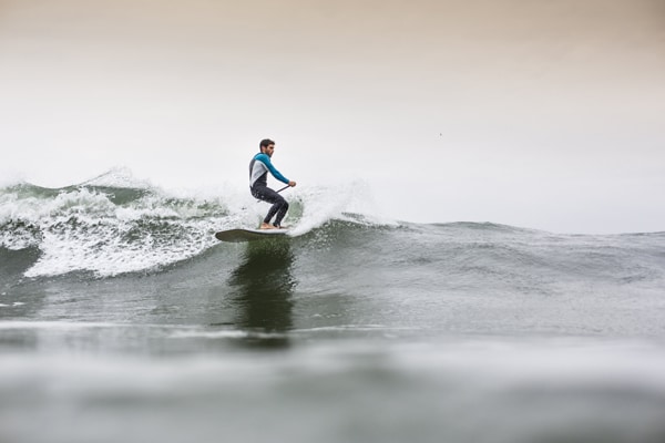 SUP Surfer catching a wave in Ericeira, Portugal with Mauka Lodge